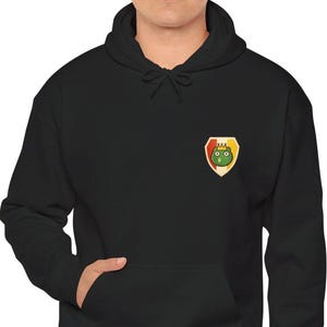 May include: Black hooded sweatshirt with a kangaroo pocket and a small emblem on the chest. The emblem features a green cartoon character with a crown on a yellow and red shield.