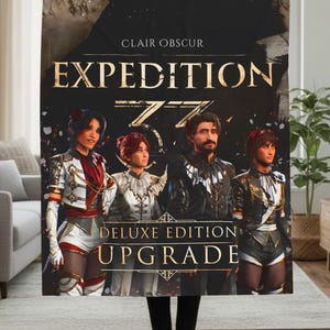 May include: A black blanket featuring the text "CLAIR OBSCUR EXPEDITION 33" in gold lettering. The blanket displays four figures in detailed costumes. Below the text are the words "DELUXE EDITION UPGRADE".