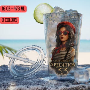 May include: Clear plastic tumbler with a lid and straw, featuring an illustration of a woman wearing a red beret and sunglasses. The tumbler holds ice and a lime slice. Text on the tumbler reads "CLAIR OBSCUR EXPEDITION 33". The tumbler is 16 oz.
