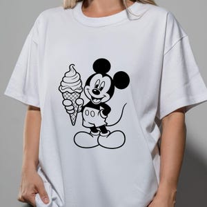 May include: White t-shirt featuring a black and white graphic of Mickey Mouse holding an ice cream cone. The cartoon character is smiling. The shirt has short sleeves and a crew neck.