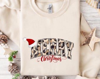 May include: Cream-colored sweatshirt with the words "MERRY Christmas" in a leopard print design. A red Santa hat is on the left side of the word "MERRY". The word "Christmas" is in a red script font.
