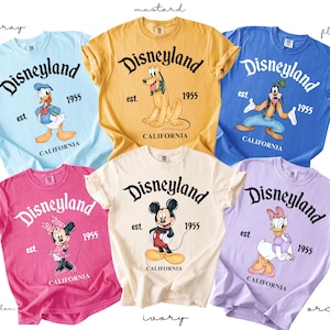 Puede incluir: Colecci&oacute;n de seis camisetas coloridas de Disneyland. Cada camiseta presenta un personaje diferente de Disney y el logotipo de Disneyland con el texto "est. 1955 CALIFORNIA". Colores: chambray, mostaza, flablue, sand&iacute;a, marfil y orqu&iacute;dea.