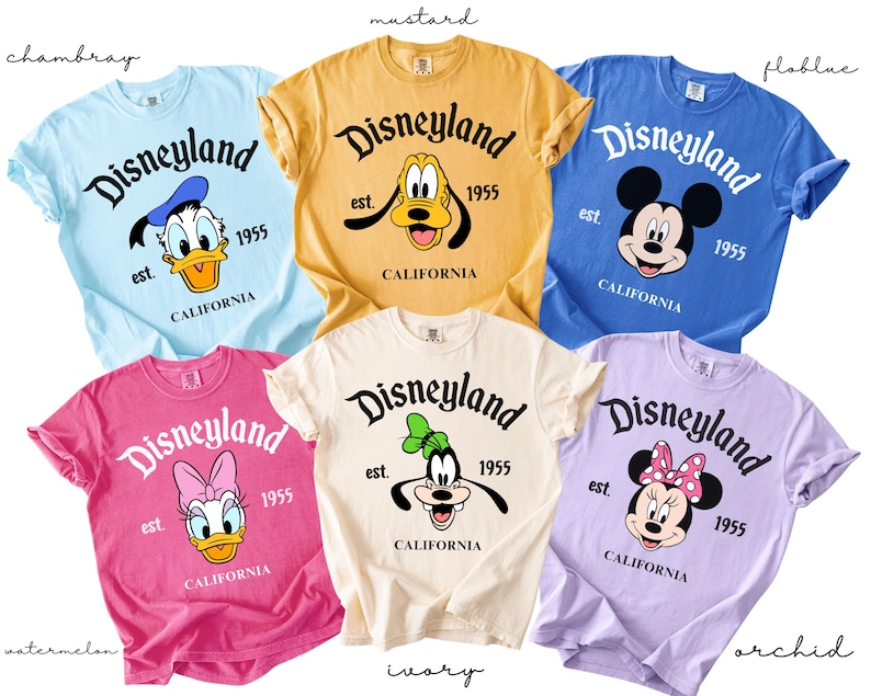 Puede incluir: Una colecci&oacute;n de camisetas coloridas con gr&aacute;ficos de Disneyland. Cada camiseta muestra un personaje diferente de Disney, incluyendo a Pato Donald, Pluto, Mickey Mouse, Daisy y Minnie Mouse. Las camisetas son de varios colores, como azul, amarillo, rosa, blanco y morado.