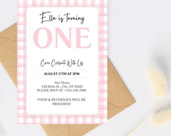 Pode incluir: Um cartão de convite rosa e branco xadrez com o texto "Ella faz UM ano". O convite inclui detalhes para uma festa de aniversário, com um envelope castanho no fundo.
