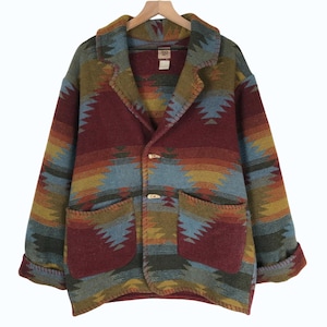Pode incluir: Um blazer de lã colorido com um padrão de inspiração sudoeste. O casaco apresenta lapelas entalhadas, dois bolsos frontais e fechos de alternância de madeira. A paleta de cores inclui tons de vermelho, azul, verde e amarelo, criando um visual vibrante e texturizado.