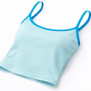 May include: A light blue camisole top with a contrasting blue trim and straps. The top is made of a soft material and is designed for comfort and style. The simple design makes it versatile for various outfits.