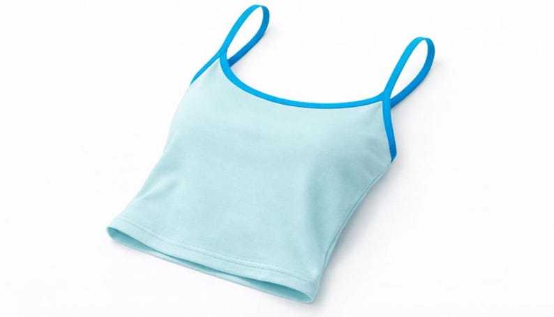May include: A light blue camisole top with a contrasting blue trim and straps. The top is made of a soft material and is designed for comfort and style. The simple design makes it versatile for various outfits.