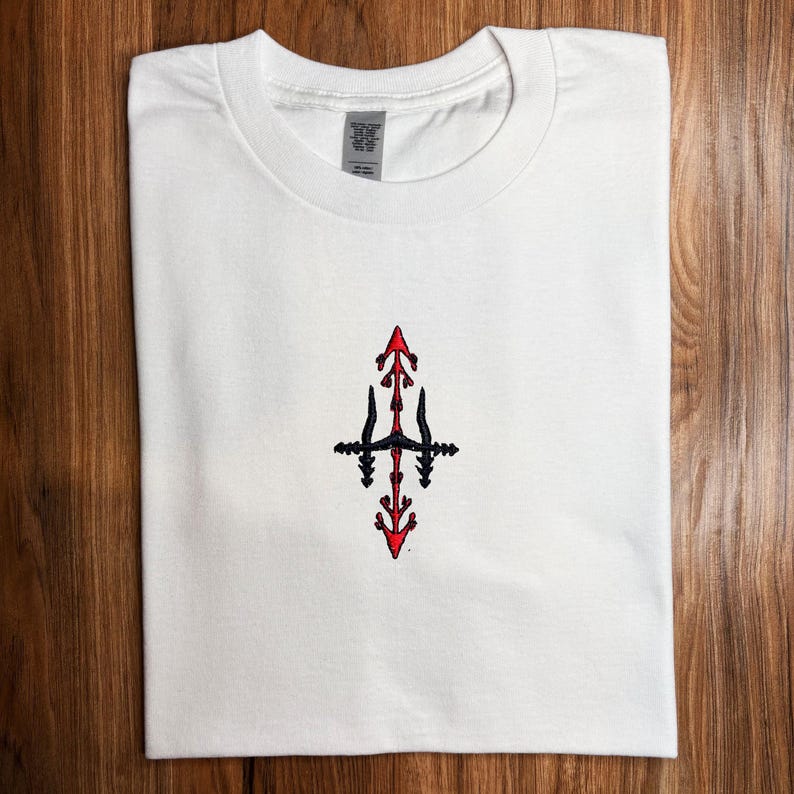 A white t-shirt with a red and black embroidered design on the front.