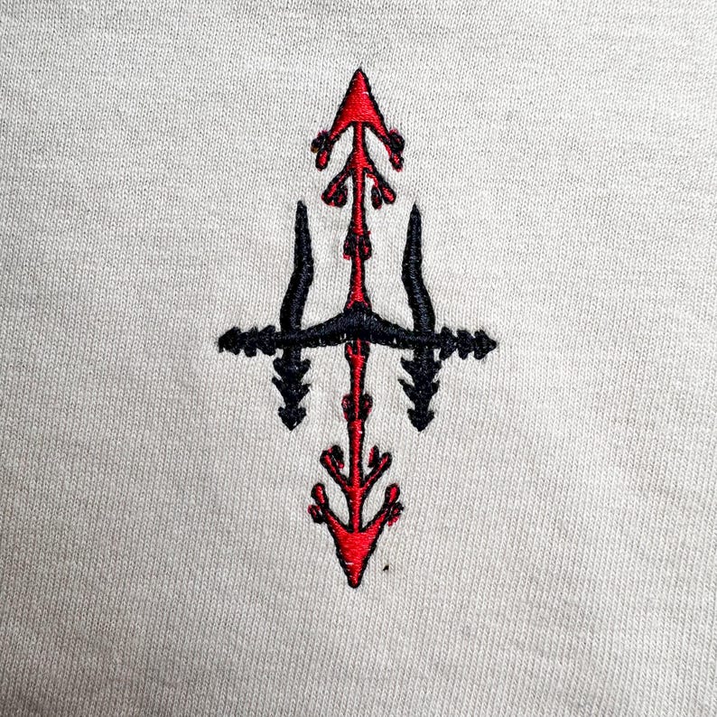 a close-up view of a white fabric with a red and black embroidered design on it.