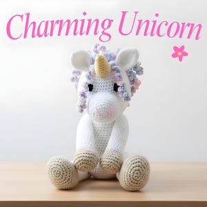 Könnte beinhalten: Ein handgefertigtes weißes Häkel-Einhorn mit goldenem Horn, das auf einer Holzoberfläche sitzt. Das Einhorn hat eine rosa Nase, schwarze Augen und bunte Garnhaare. Der Text "Charming Unicorn" steht darüber.