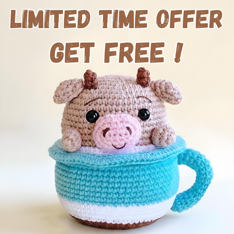 May include: A crocheted cow toy in a blue and white cup. The cow is light brown with a pink nose and black eyes. The cup has a blue handle and the text "LIMITED TIME OFFER GET FREE!"