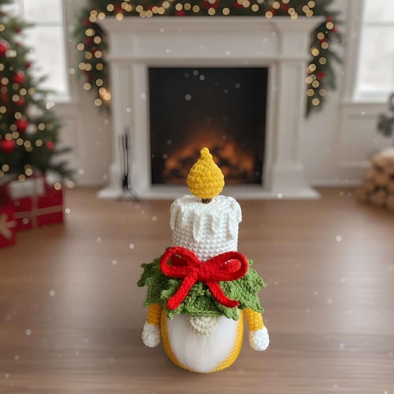 May include: A crocheted candle gnome with a yellow flame, white candle body, and a green wreath with a red bow. The gnome has a white beard, yellow body, and white hands. The festive decoration is set against a blurred background.