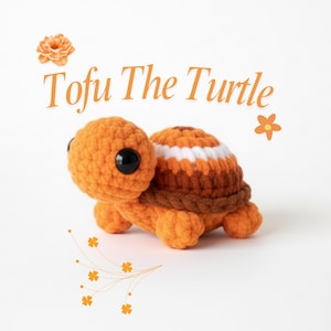 May include: A crocheted turtle in shades of orange and brown, with a white and brown striped shell. The text "Tofu The Turtle" is written above the turtle. The turtle has large black eyes.