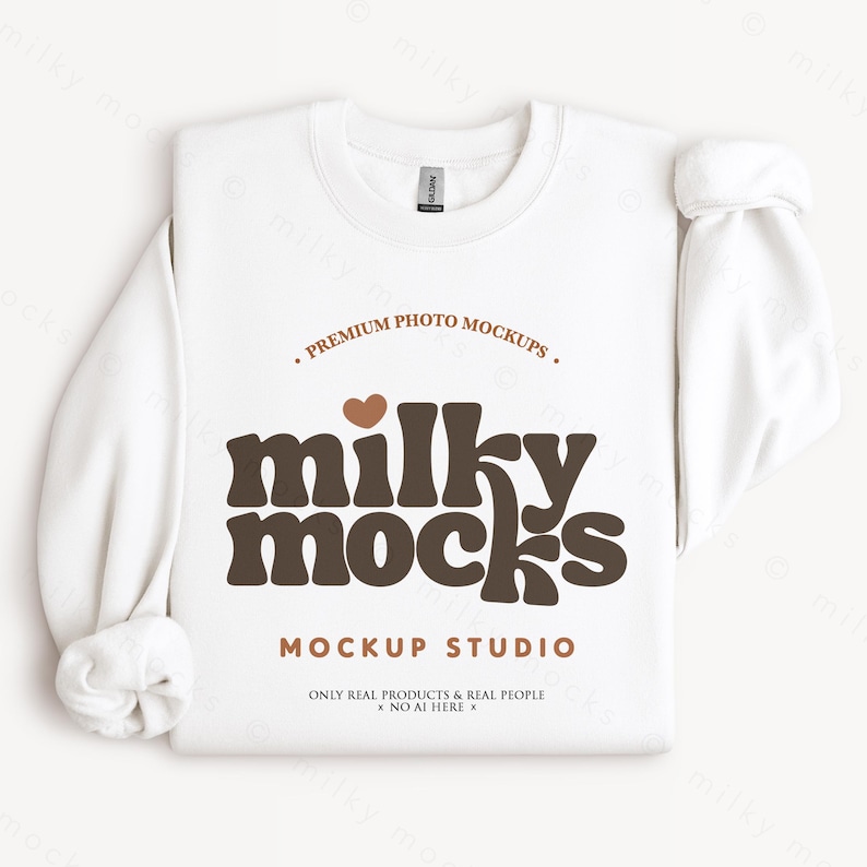 K&ouml;nnte beinhalten: Ein wei&szlig;es Sweatshirt mit Rundhalsausschnitt und dem braunen Text "milky mocks", "PREMIUM PHOTO MOCKUPS" und "MOCKUP STUDIO". Die &Auml;rmel sind hochgekrempelt. Das Etikett lautet "GILDAN".