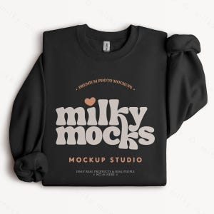 K&ouml;nnte beinhalten: Schwarzes Sweatshirt mit Rundhalsausschnitt und dem Text "milky mocks" in Retro-Schrift, einem Herz und den S&auml;tzen "Premium Photo Mockups", "Mockup Studio" und "Only Real Products & Real People * No AI Here".
