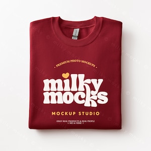 May include: A folded burgundy sweatshirt with the text "milky mocks" in a white, retro font. The text "PREMIUM PHOTO MOCKUPS" and "MOCKUP STUDIO" are also visible. A small yellow heart is above the word "milky".