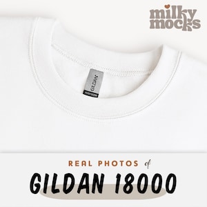 K&ouml;nnte beinhalten: Nahaufnahme eines wei&szlig;en Gildan 18000 Sweatshirts. Das Sweatshirt hat einen Rundhalsausschnitt und ein Etikett mit der Aufschrift "GILDAN HEAVY BLEND". Der Text "REAL PHOTOS of GILDAN 18000" befindet sich am unteren Bildrand.
