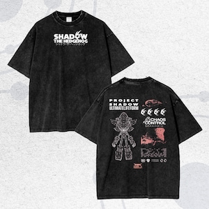 May include: Black t-shirt featuring the text "SHADOW THE HEDGEHOG" in white, with Japanese text below. The back of the shirt displays "PROJECT SHADOW ULTIMATELIFEFORM" and a graphic of a character, along with the text "CHAOS CONTROL".