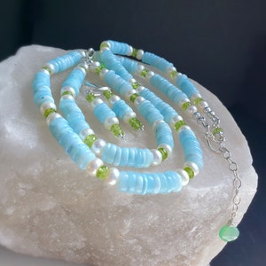 K&ouml;nnte beinhalten: Ein Set aus blauem und wei&szlig;em Edelsteinschmuck mit gr&uuml;nen Akzenten. Das Set beinhaltet eine Halskette, ein Armband und Ohrringe.