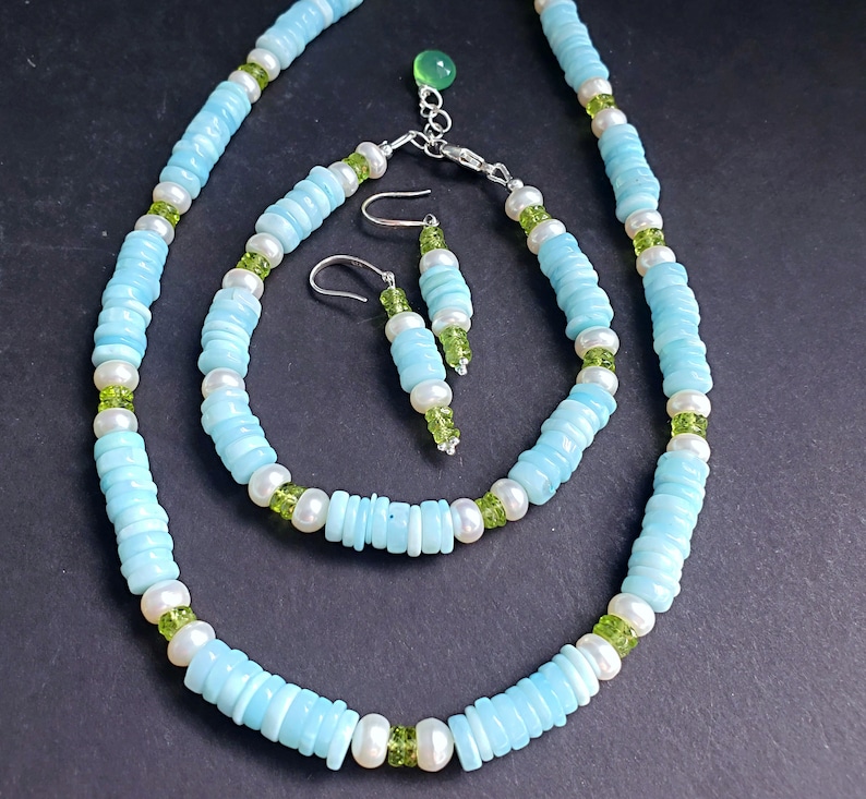 K&ouml;nnte beinhalten: Ein Schmuckset aus t&uuml;rkisfarbenen und gr&uuml;nen Edelsteinen mit einer Halskette, einem Armband und Ohrringen. Die Halskette und das Armband bestehen aus t&uuml;rkisfarbenen und wei&szlig;en Perlen, w&auml;hrend die Ohrringe aus t&uuml;rkisfarbenen und gr&uuml;nen Perlen bestehen.