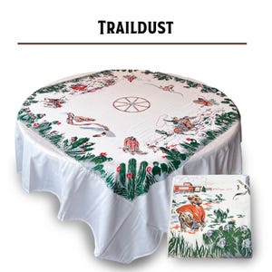 May include: White round tablecloth with a western-themed design. The tablecloth features illustrations of cacti, cowboys, and a wagon wheel. The word "TRAILDUST" is printed at the top. A folded matching napkin is also shown.