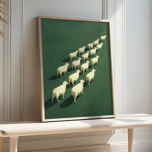 May include: A framed art print featuring a flock of white sheep walking diagonally across a green field. The artwork has a minimalist style with a light wooden frame, displayed on a light wood bench.