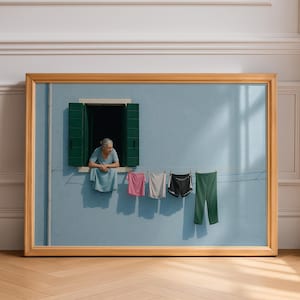 Peut inclure: Une œuvre d'art encadrée représente une femme regardant par une fenêtre avec des volets verts. Des vêtements sont suspendus à une corde à linge à l'extérieur de la fenêtre. Le mur est bleu clair et le cadre est doré.