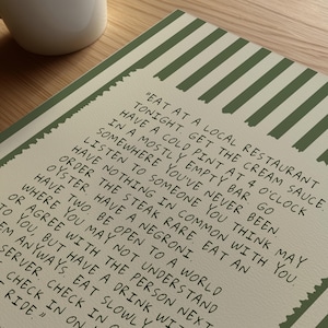 Striped Anthony Bourdain typography poster with handwritten text on a warm cream background featuring olive green, navy blue, and charcoal black colour variations. Vintage-inspired kitchen wall art with subtle stripe details and European cafe aesthetic displayed in wooden frames inside cozy interiors. Minimal quote print designed for coffee corners, dining rooms, bookstores, restaurants, and modern apartments with warm lighting and neutral decor styling.