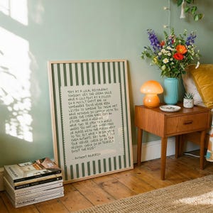 Striped Anthony Bourdain typography poster with handwritten text on a warm cream background featuring olive green, navy blue, and charcoal black colour variations. Vintage-inspired kitchen wall art with subtle stripe details and European cafe aesthetic displayed in wooden frames inside cozy interiors. Minimal quote print designed for coffee corners, dining rooms, bookstores, restaurants, and modern apartments with warm lighting and neutral decor styling.