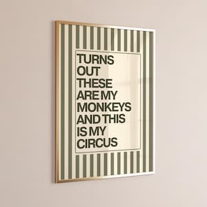 Puede incluir: Un estampado enmarcado con el texto "TURNS OUT THESE ARE MY MONKEYS AND THIS IS MY CIRCUS." El estampado tiene un marco dorado y un fondo a rayas en tonos verdes y crema.