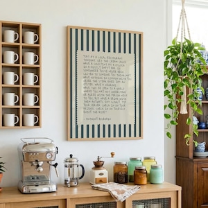 Striped Anthony Bourdain typography poster with handwritten text on a warm cream background featuring olive green, navy blue, and charcoal black colour variations. Vintage-inspired kitchen wall art with subtle stripe details and European cafe aesthetic displayed in wooden frames inside cozy interiors. Minimal quote print designed for coffee corners, dining rooms, bookstores, restaurants, and modern apartments with warm lighting and neutral decor styling.