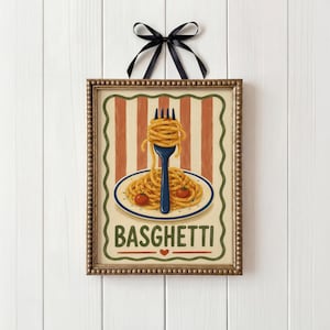 May include: A framed picture of spaghetti on a plate with two tomatoes and a fork. The background has orange and cream stripes. The word "BASGHETTI" is at the bottom. A black ribbon is at the top.