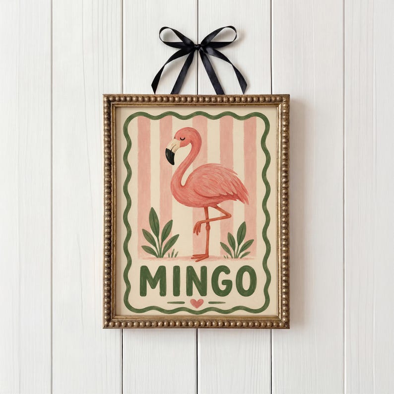 May include: A framed print with a pink flamingo illustration on a pink and white striped background. The word "MINGO" is written in green below the flamingo, with a heart symbol. The frame is gold, and a black ribbon is attached.