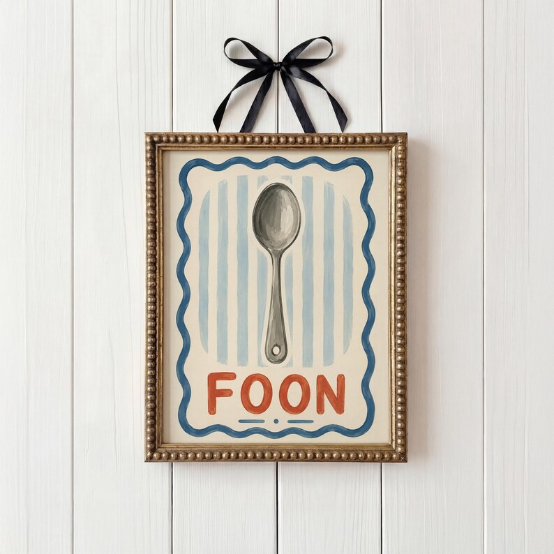 May include: A framed print with a spoon illustration. The artwork has a gold-coloured frame and a blue and white striped background. The word "FOON" is written in red letters at the bottom. A black ribbon is tied at the top.