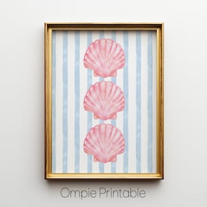 May include: A framed print featuring three pink seashell illustrations on a light blue and white striped background. The artwork is in a gold frame and includes the text "Ompie Printable" at the bottom.