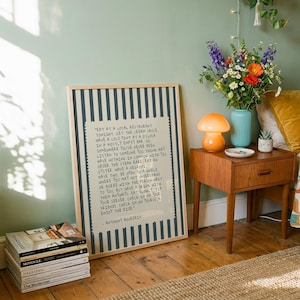 Striped Anthony Bourdain typography poster with handwritten text on a warm cream background featuring olive green, navy blue, and charcoal black colour variations. Vintage-inspired kitchen wall art with subtle stripe details and European cafe aesthetic displayed in wooden frames inside cozy interiors. Minimal quote print designed for coffee corners, dining rooms, bookstores, restaurants, and modern apartments with warm lighting and neutral decor styling.