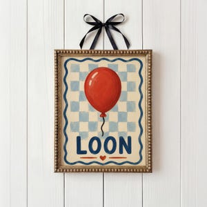 May include: A framed art print with a red balloon on a blue and white chequered background. The word "LOON" is written in blue letters below the balloon, with a red heart. The frame is gold with a black ribbon.