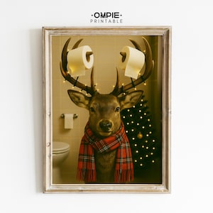 May include: A framed print depicting a deer with toilet paper rolls on its antlers and fairy lights. The deer wears a red plaid scarf. A Christmas tree and bathroom fixtures are in the background. The print has a humorous, festive theme.