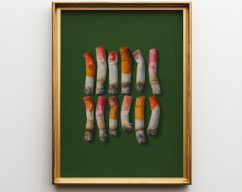 May include: A framed print featuring a collection of cigarette butts against a dark green background. The butts are various shades of white, orange, and red, with visible ash. The frame is gold, and the text "Ompie Printable" is at the bottom.