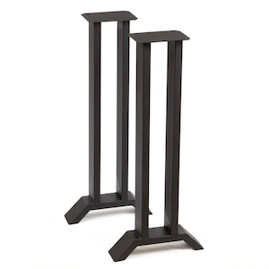 May include: Two dark brown metal speaker stands. Each stand has a rectangular top and base, connected by three vertical supports. The stands are designed to elevate speakers, enhancing audio quality and creating a modern aesthetic.