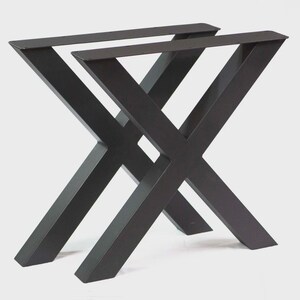 May include: Two black metal table legs in an X-shape design. The legs are made of thick, sturdy metal and are designed to support a tabletop. The legs are painted in a matte black finish, giving them a modern look.