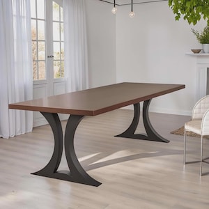 May include: A rectangular dining table with a brown tabletop and black, curved pedestal legs. The table is in a well-lit room with white curtains and a light-colored floor. The table is approximately 96 inches long.