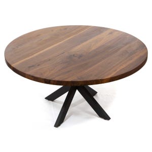 May include: A round wooden table with a dark brown finish. The table has a black metal base with a starburst design. The table is a medium size, suitable for a dining room or kitchen.
