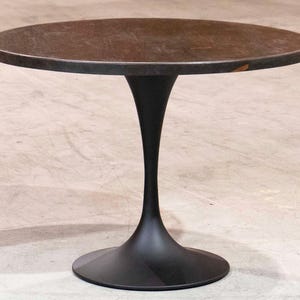 May include: A round, dark brown table with a black, tulip-shaped base. The tabletop appears to be made of a textured material. The table is approximately 30 inches in diameter and stands about 28 inches tall.