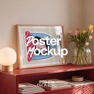Peut inclure: Maquette d'affiche encadrée avec le texte "Poster Mockup" sur un meuble rouge. Un vase en verre avec des tulipes jaunes et roses est à côté de l'affiche. Une petite lampe ronde et une pile de livres sont également sur le meuble.