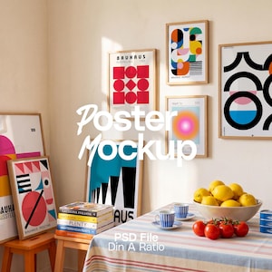 May include: A collection of framed posters with geometric Bauhaus-style designs displayed on a wall and on wooden stools. A table in the foreground features a bowl of yellow lemons, red tomatoes on the vine, two blue striped cups, and a bottle of oil.
