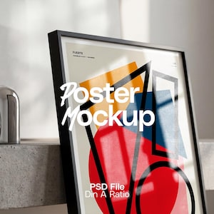 May include: A black framed poster mockup with a colorful abstract design featuring orange, blue, and red shapes. The words "Poster Mockup" are displayed in white script. The poster is leaning against a concrete surface.