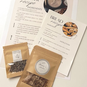 May include: A still-life image featuring two small brown paper bags with labels, alongside two recipe cards. One bag is labeled "Culinary Lavender," the other "Mama's Starter." The recipe cards detail bread and starter recipes.