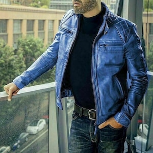 Op de afbeelding: Blau leren jas met een gewatteerd schouderontwerp en een opstaande kraag. De jas heeft een ritssluiting en meerdere zakken. Het model draagt een zwart shirt en een blauwe jeans. De jas is een stijlvolle buitenkleding.