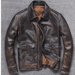 Könnte beinhalten: Braune Lederjacke mit einem abgenutzten, Vintage-Look. Die Jacke hat einen Kragen, einen Reißverschluss vorne, zwei Vordertaschen und ein braunes Innenfutter. Das Leder hat einen abgenutzten, strukturierten Look.